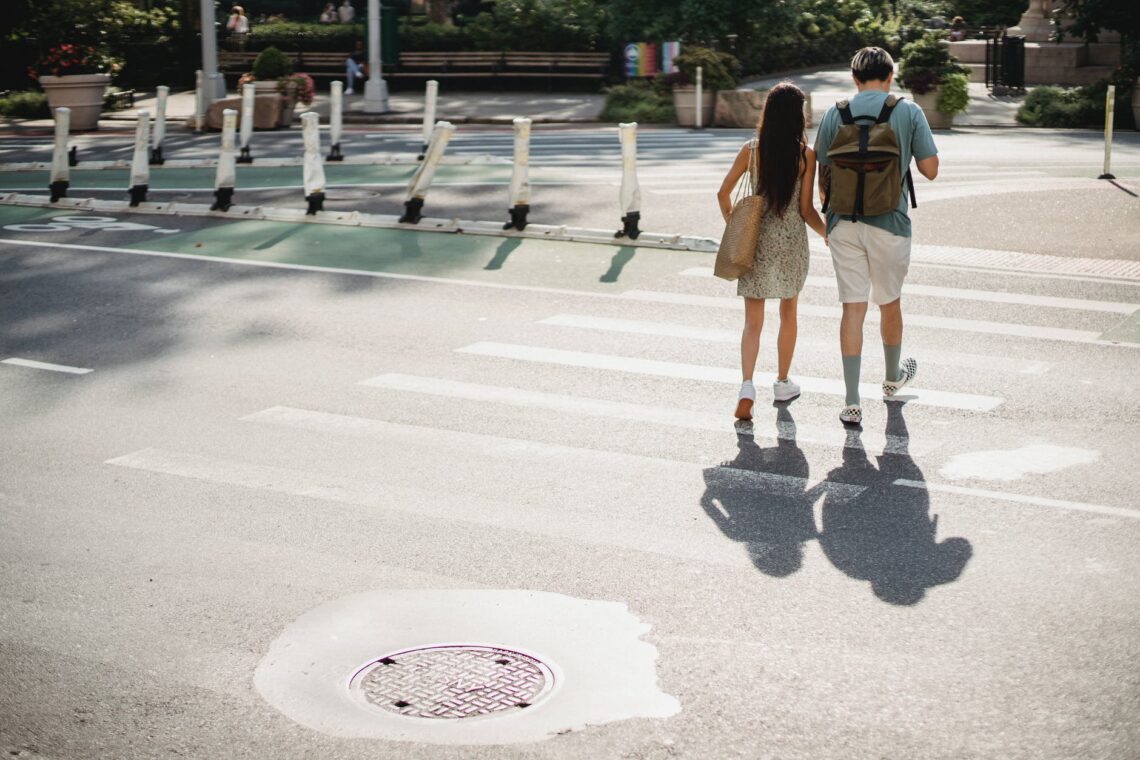 unrecognizable couple crossing road in sunny city